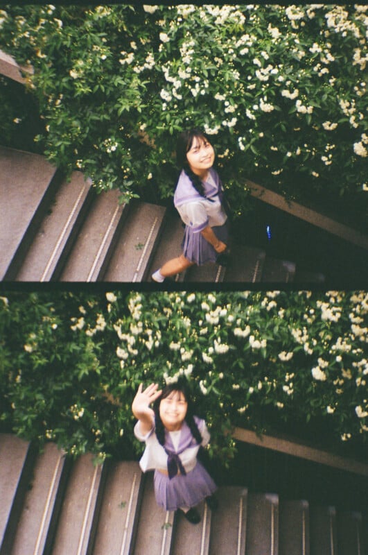 Two images of a person in a school uniform with long black hair in braids, standing on stairs next to a bush with white flowers. In the first image, the person looks upward smiling, and in the second, they raise a hand in greeting.