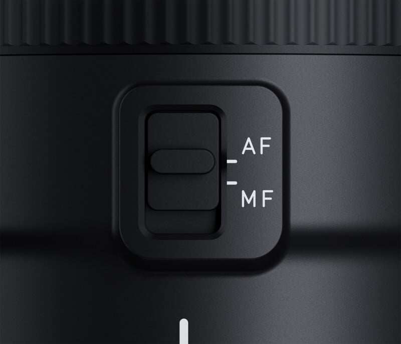 Close-up of a camera lens with a switch labeled "AF" for autofocus and "MF" for manual focus. The switch is currently in the AF position, on a smooth, black surface.