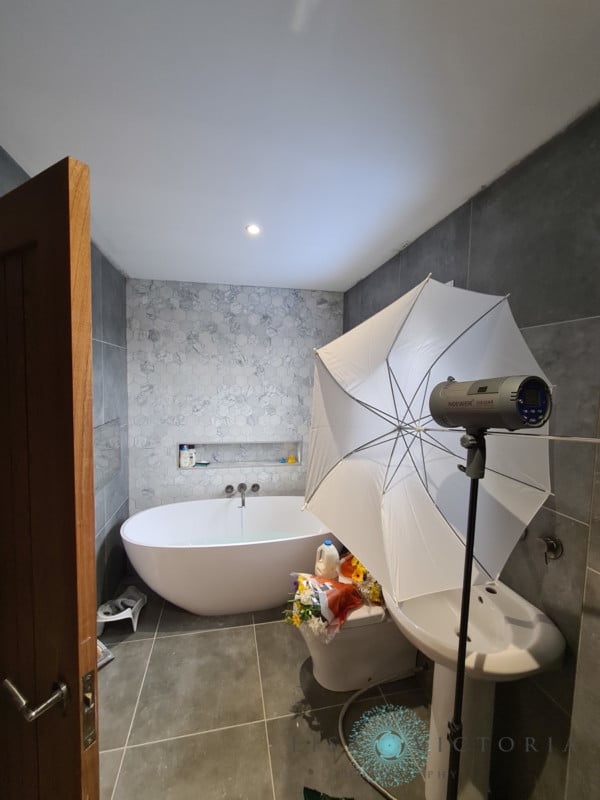 A strobe with white umbrella in a bathroom in preparation for a milk bath photo shoot