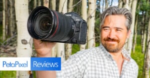 A person with gray hair and a beard holds up a Canon EOS R5 camera against a background of trees. The photo includes a "PetaPixel Reviews" logo in the bottom left corner.