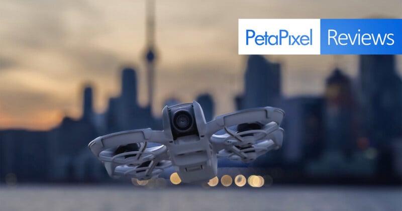 A drone hovers in the foreground with a blurred city skyline and sunset in the background. The image features a "PetaPixel Reviews" banner in the top right corner.