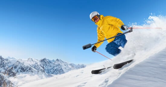 A skier shreds down a snowy mountain slope while holding the Insta360 Ski Pole Mount.