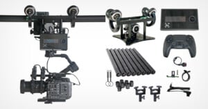 A camera rig setup with rails, a camera mount, a touch screen controller, and various accessories including a joystick-style controller, cables, connectors, and mounting brackets, all laid out against a white background.