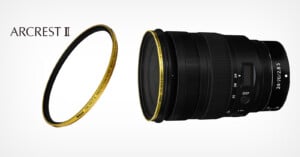 A black camera lens with a digital display, labeled "24-70/2.8 S," is shown alongside a separate circular lens filter with a gold rim. The text "ARCREST II" is in the top left corner.