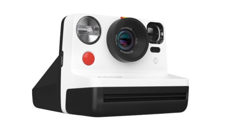 A retro-style instant camera with a white and black body, large round lens, and flash. The camera has a rainbow stripe and a viewfinder on top.