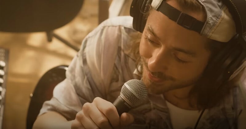 A person wearing headphones and a cap is singing into a microphone. They are captured from a top angle, appearing focused and engaged in the performance.