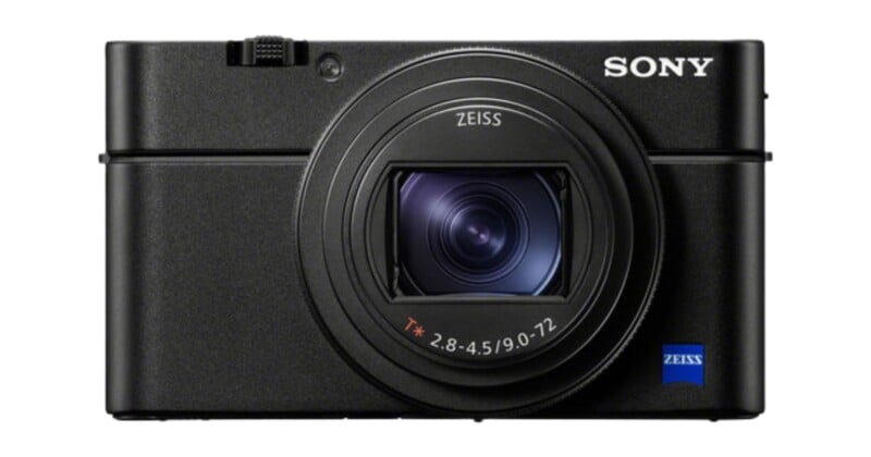 A black Sony camera with a Zeiss lens is shown from the front. The camera features a textured grip and is compact in design. The brand and lens logos are visible on the camera body.