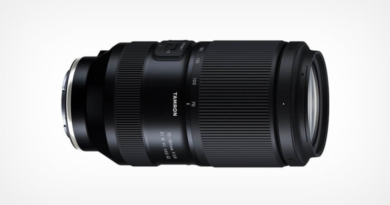 A black Tamron camera lens with visible zoom markings from 70 to 180mm and a maximum aperture of f/2.8. The lens has a ribbed texture for grip and a silver mount. The brand name is printed on the side.