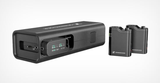 Image of a Sennheiser wireless microphone system showing a rectangular charging case and two compact black transmitters with small screens and labeled buttons.