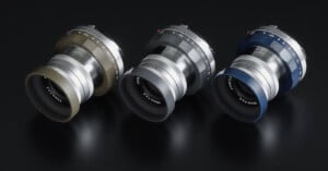 Three camera lenses with metal bodies are displayed on a dark surface. The lenses come in different colors: green, silver, and blue. Each lens has detailed engravings and a sleek design, showcasing precision craftsmanship.